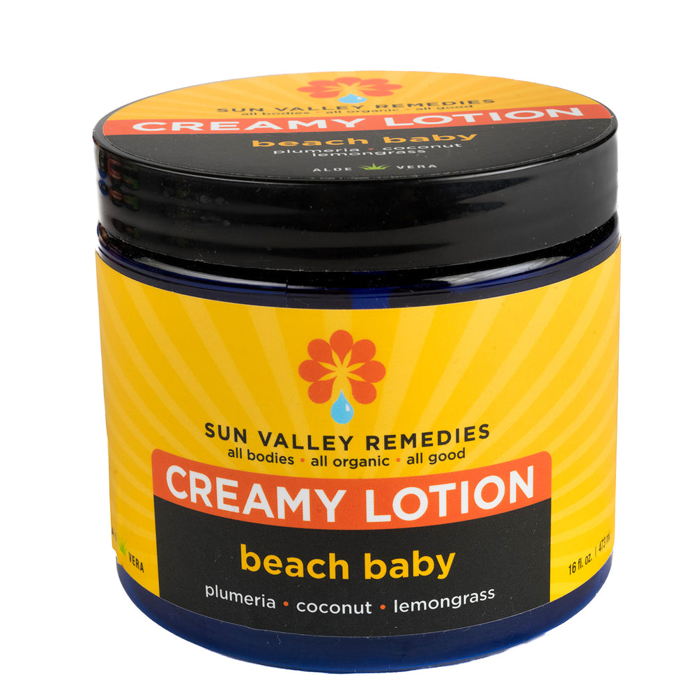 Sixteen ounce cobalt jar of Beach Baby Creamy Lotion.  The label indicates the aromatherapy is plumeria, coconut, lemongrass