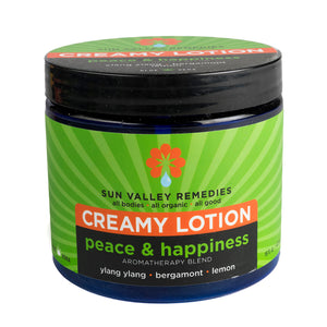 Sixteen ounce cobalt jar of Peace and Happiness lotion. The label indicates the aromatherapy is ylang ylang, bergamot, lemon