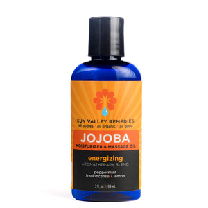 Two ounce cobalt bottle of Energizing Jojoba oil. The label indicates the aromatherapy is peppermint, frankincense, and lemon