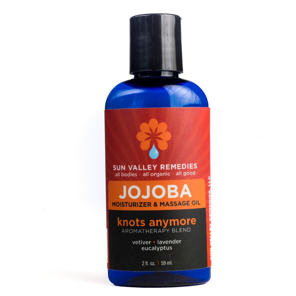 Two ounce cobalt bottle of Knots Anymore Jojoba oil. The label indicates the aromatherapy is vetiver, lavender, eucalyptus