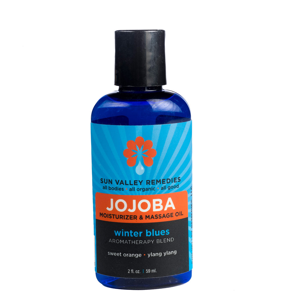Two ounce cobalt bottle of Winter Blues Jojoba oil. The blue label indicates the aromatherapy is sweet orange and ylang ylang