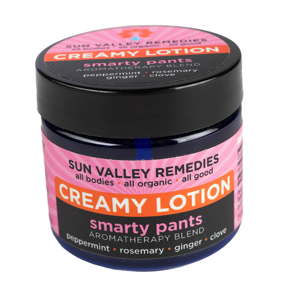 Two ounce cobalt jar of Smarty Pants lotion. The label indicates the aromatherapy is peppermint, rosemary, ginger, and clove