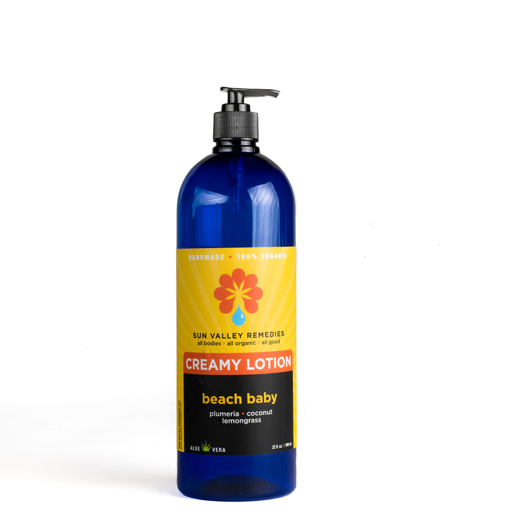 Thirty two ounce cobalt bottle of Beach Baby Lotion.  The label indicates the aromatherapy is plumeria, coconut, lemongrass