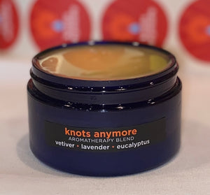 Four ounce cobalt jar of Knots Anymore Himalayan Salt Scrub. The label indicates aromatherapy of vetiver, lavender, eucalyptus