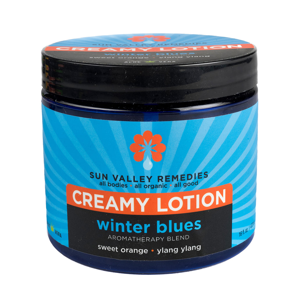 Sixteen ounce cobalt jar of Winter Blues lotion. The blue label indicates the aromatherapy is sweet orange and ylang ylang