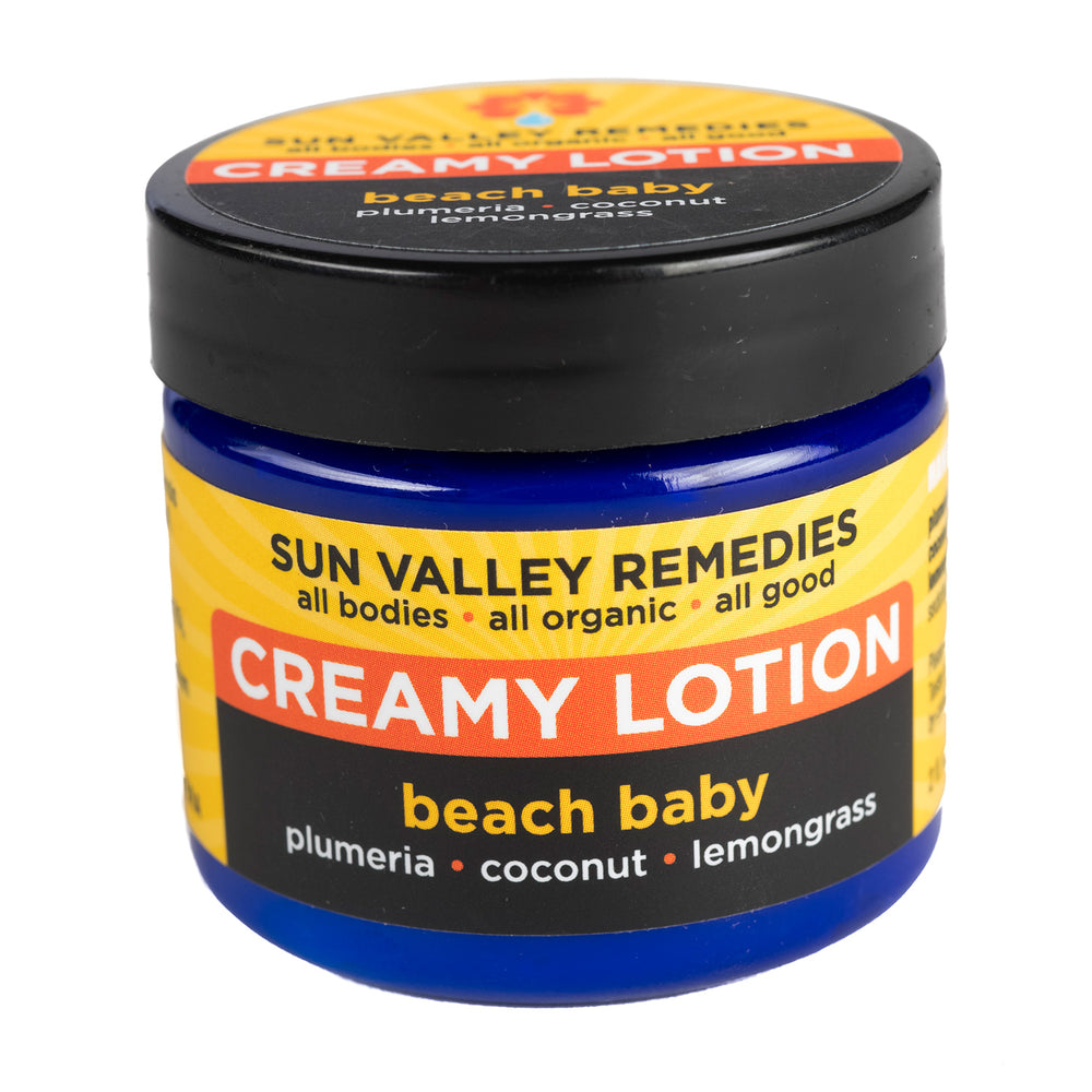 Two ounce cobalt jar of Beach Baby Creamy Lotion.  The label indicates the aromatherapy is plumeria, coconut, and lemongrass