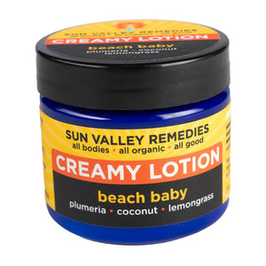 Two ounce cobalt jar of Beach Baby Creamy Lotion. The label indicates the aromatherapy is plumeria, coconut, and lemongrass