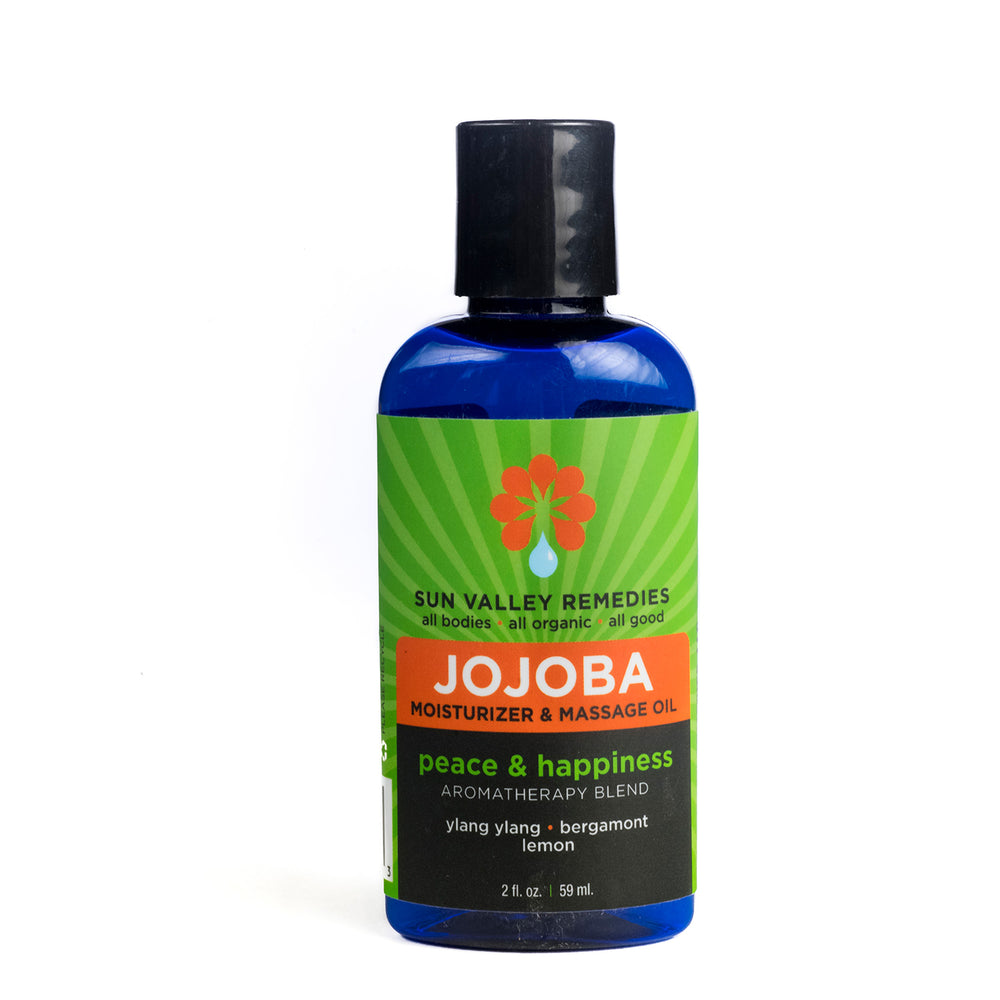 Two ounce cobalt bottle of Peace and Happiness Jojoba oil. The label indicates the aromatherapy is ylang ylang, bergamot, lemon