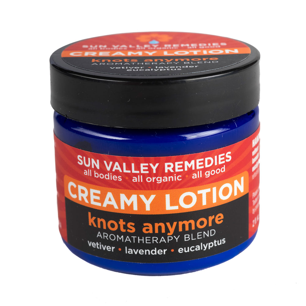 Two ounce cobalt blue jar of Knots Anymore lotion. The label indicates the aromatherapy is vetiver, lavender, and eucalyptus