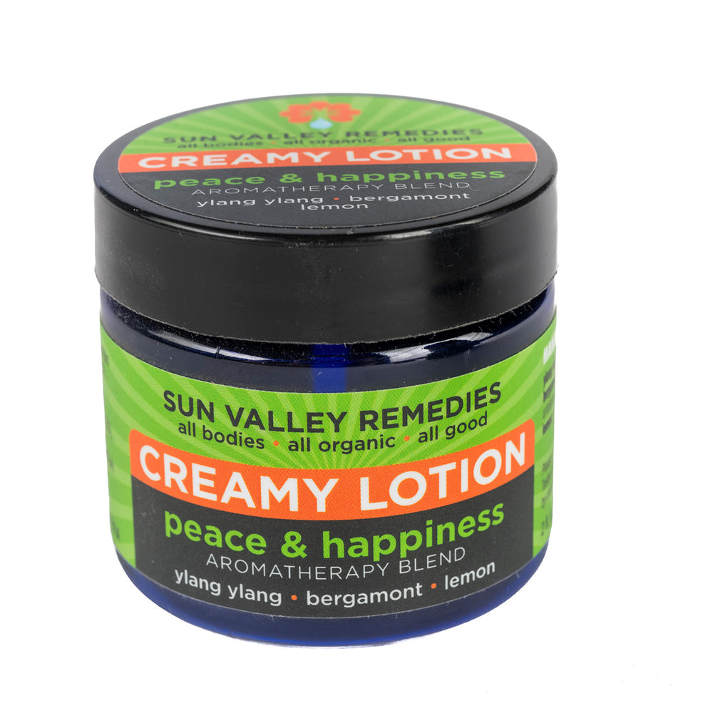 Two ounce cobalt jar of Peace and Happiness lotion. The label indicates the aromatherapy is ylang ylang, bergamot, and lemon