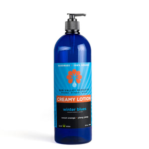 
            
                Load image into Gallery viewer, Thirty two ounce cobalt bottle of Winter Blues lotion. The label indicates the aromatherapy is sweet orange and ylang ylang
            
        