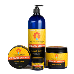 Four cobalt jars and bottles of Beach Baby Lotion. The label indicates the aromatherapy is plumeria, coconut, and lemongrass