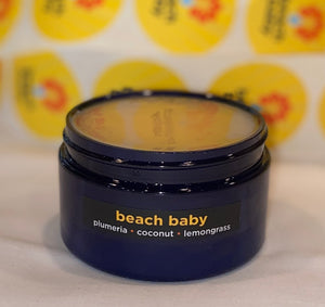 Four ounce cobalt jar of Beach Baby Himalayan Salt Scrub. The label indicates aromatherapy of plumeria, coconut, lemongrass