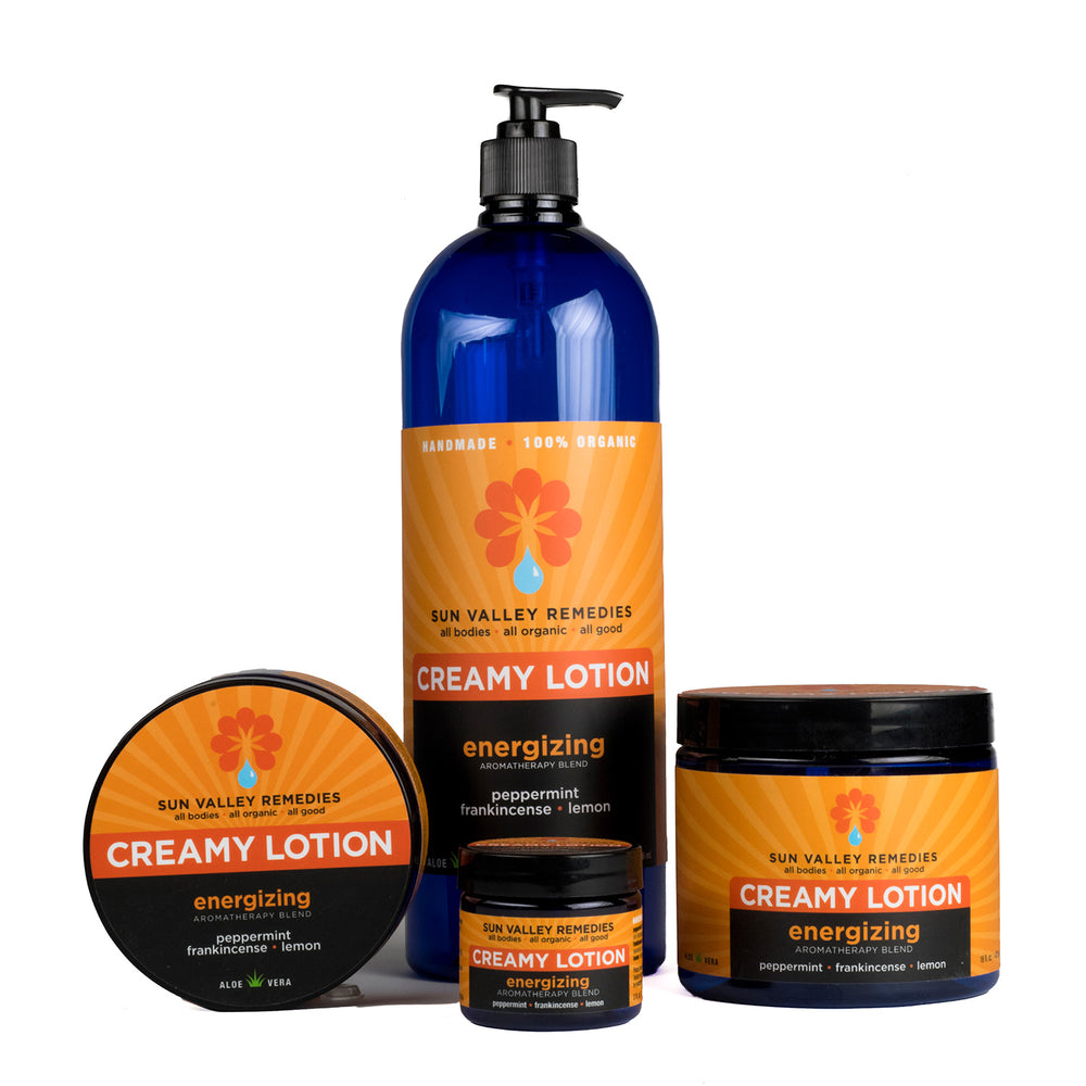 Four cobalt containers of Energizing Lotion. The orange label indicates the aromatherapy is peppermint, frankincense, lemon