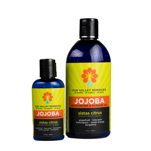 Two cobalt bottles of Sistas Citrus Jojoba. The lime label indicates the aromatherapy is grapefruit lime peel lemongrass sweet orange bergamot
