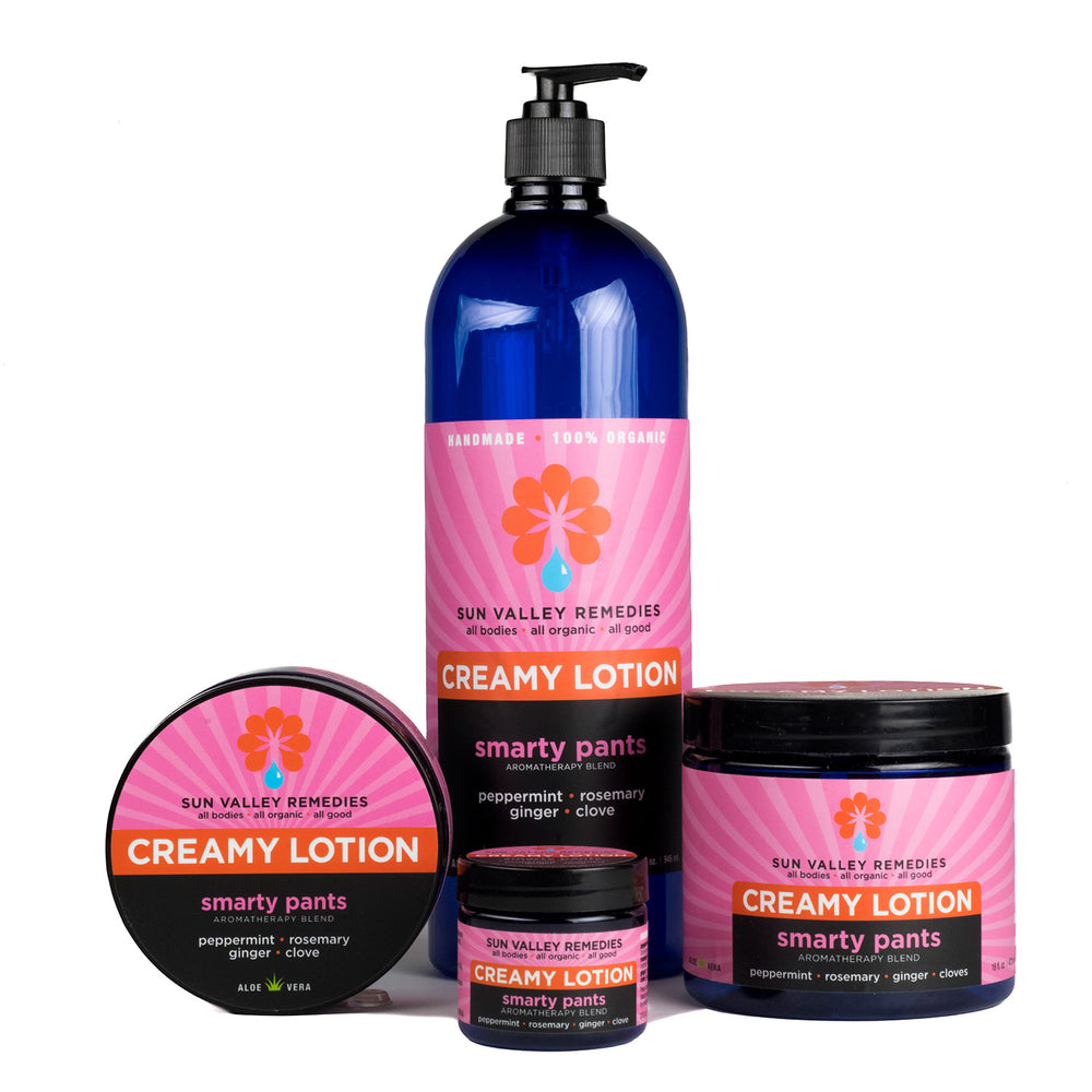 Four cobalt containers of Smarty Pants Lotion. The pink label indicates the aromatherapy is peppermint, rosemary, ginger, clove